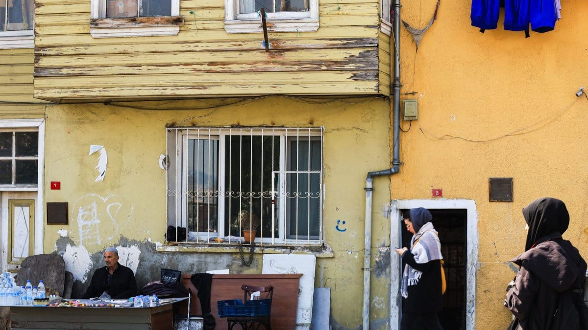 Daily life on a bustling street in Istanbul, featuring local architecture and residents walking by.