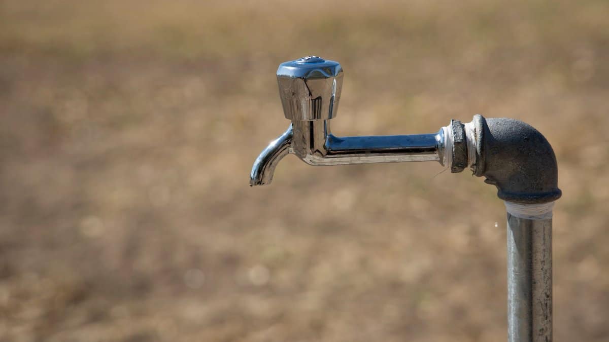 Close-up of a metal water faucet in an outdoor setting, highlighting its rustic charm and simplicity.