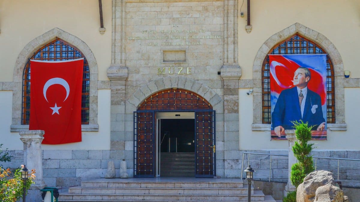 Entrance of a Turkish museum with national flags and stone architecture.