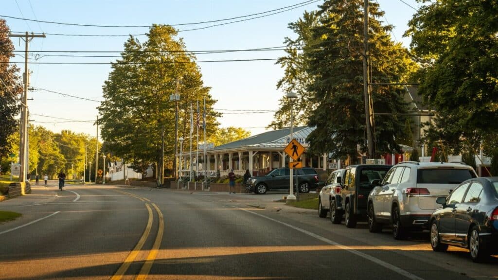 Cozy street view in Holland, Michigan showcasing parked cars, trees, and clear evening light.