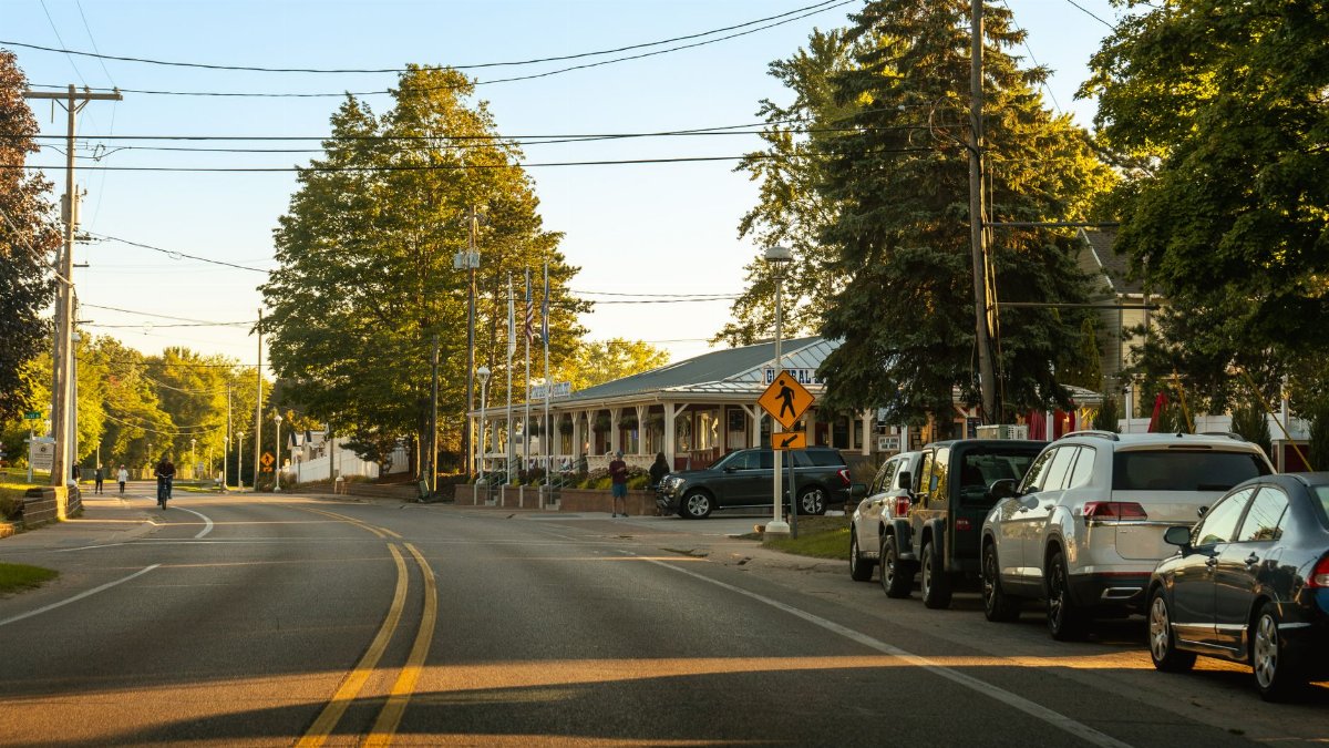 Cozy street view in Holland, Michigan showcasing parked cars, trees, and clear evening light.