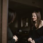 A woman expressing emotions at a doorway, another person partially visible.