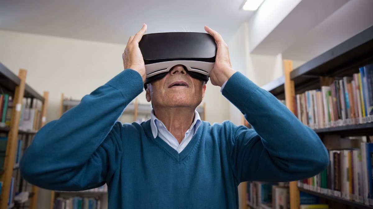 A senior man enjoying a virtual reality experience in a library setting.