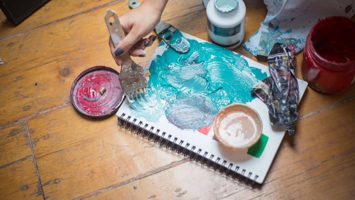 A hand painting with bold colors on a sketchbook, showcasing artistic creativity.