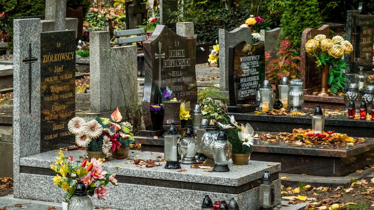 Serene cemetery scene featuring beautifully decorated graves with colorful flowers and lanterns.