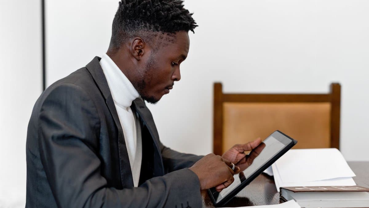 Businessman in elegant suit using tablet during office meeting, focusing on touchscreen technology.