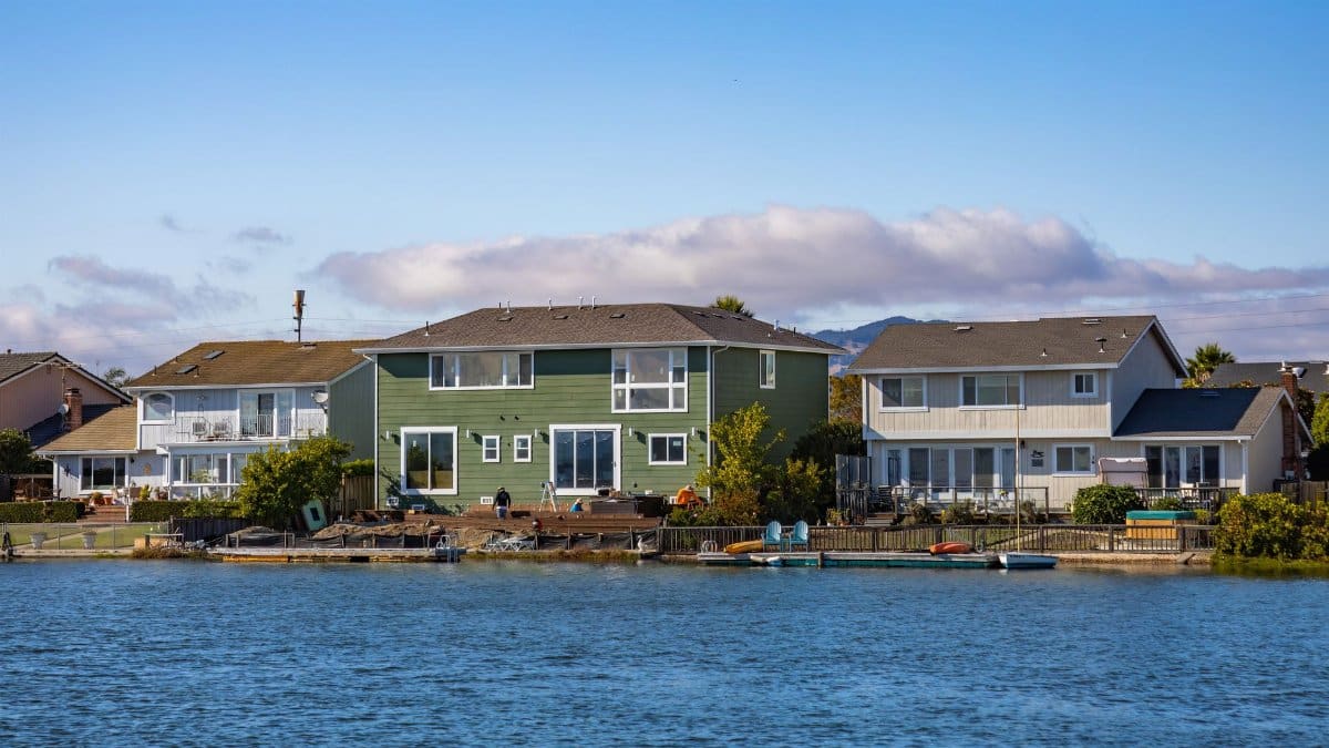 Picturesque riverside homes with clear blue skies and calm water in a peaceful neighborhood.