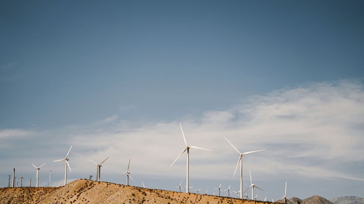 Stunning view of wind turbines on a desert hill under a clear blue sky, showcasing renewable energy.