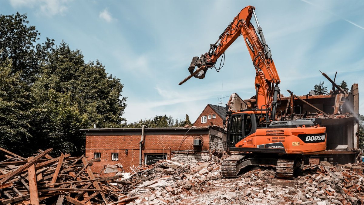 Excavator demolishing a building in Geesthacht, Germany, showcasing urban redevelopment and construction industry dynamics.