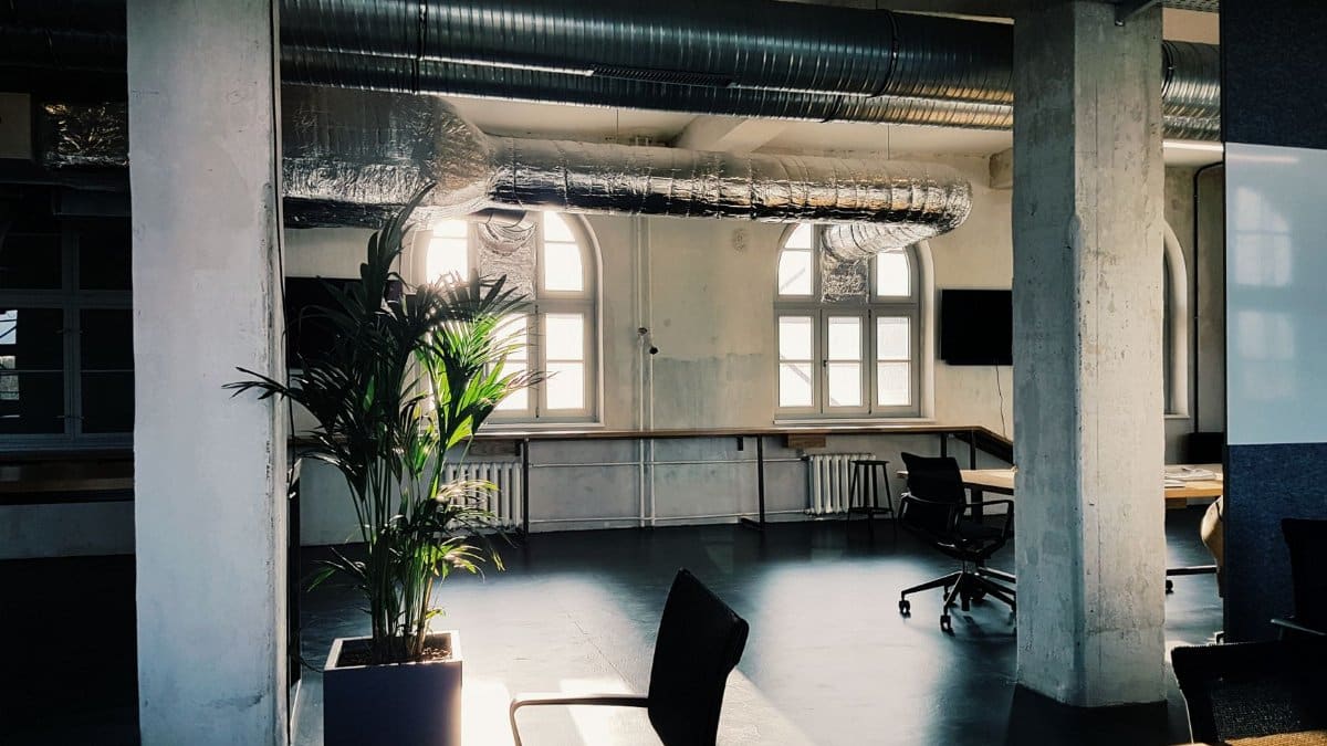 Bright modern office interior with industrial design elements and natural light through large windows.