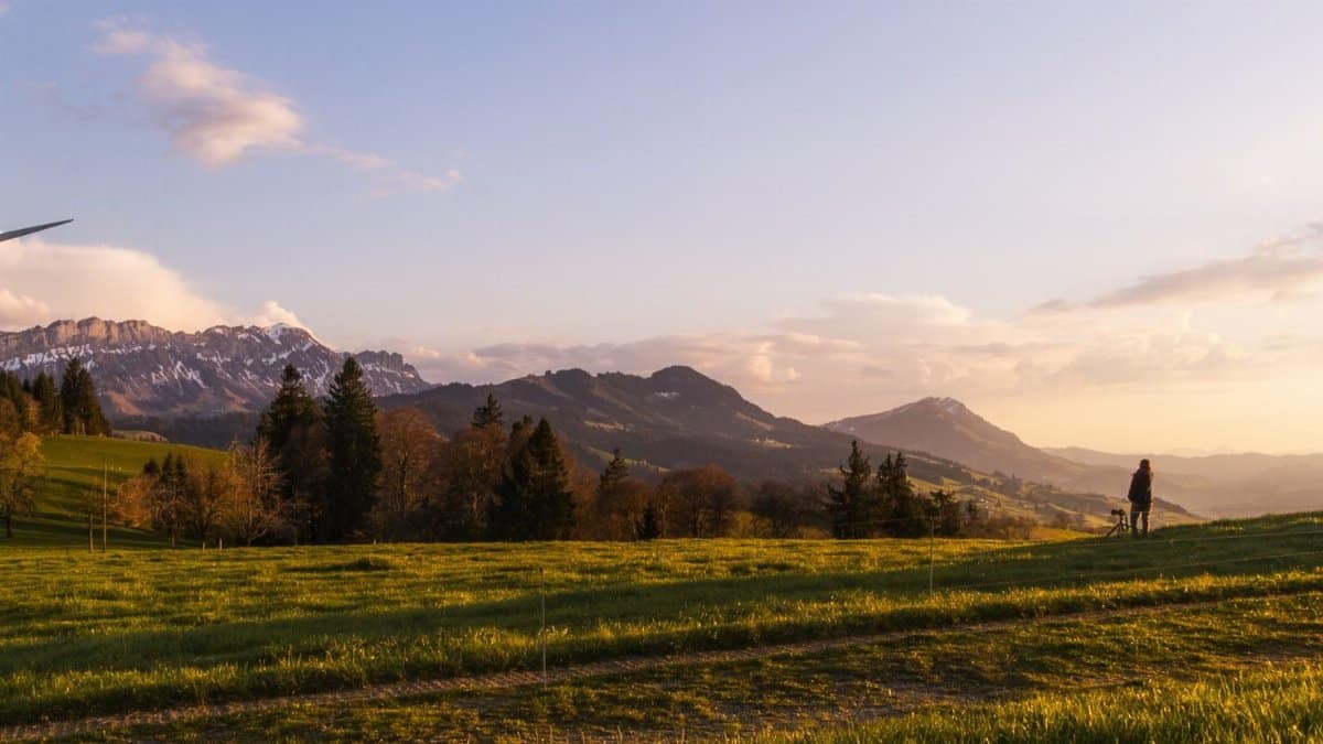 Wind turbine in Swiss landscape at sunset promotes renewable energy and environmental conservation.