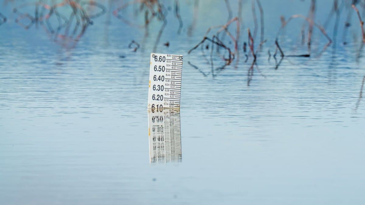 Close-up of a flood gauge in water, reflecting calm surroundings. Perfect for environmental themes.