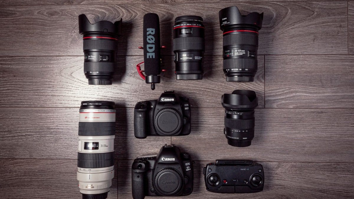 Flat lay of professional photography equipment including cameras, lenses, and microphone.