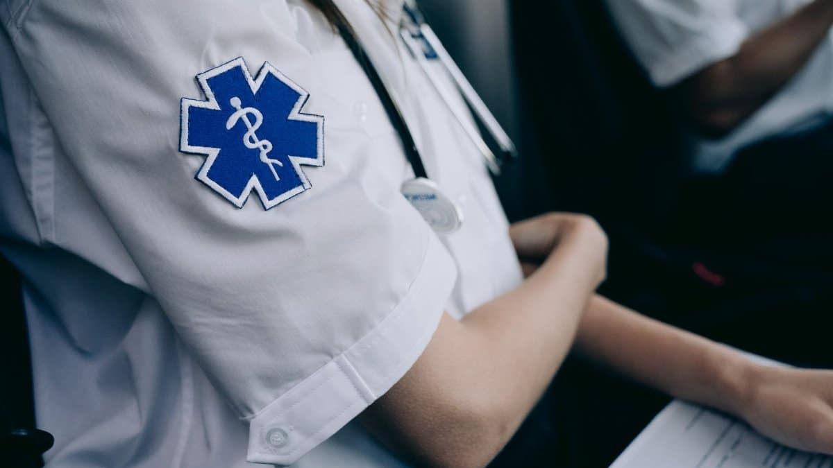Paramedics in uniform work with medical charts inside an ambulance.