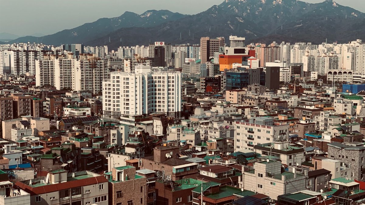 Aerial cityscape of Seoul with mountains, showcasing the urban density and architecture.