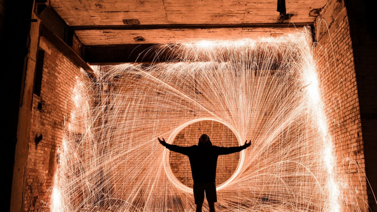 A captivating long exposure shot with a silhouetted person and spark trails from steel wool photography.