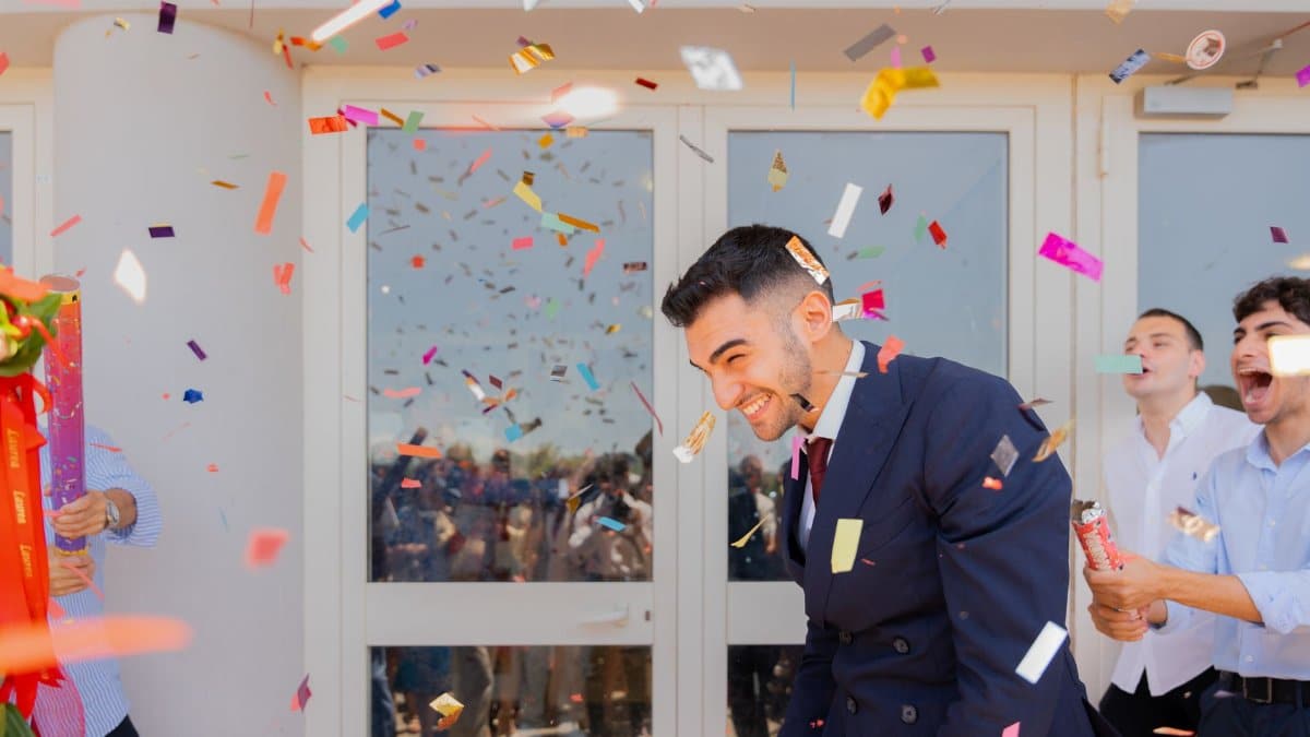 Group of adults celebrating with confetti outdoors in bright light, creating a festive and joyful atmosphere.