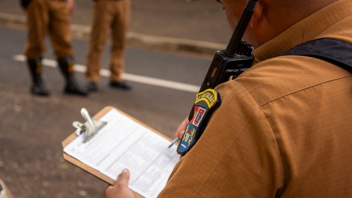 Close-up of a police officer writing on a clipboard outdoors in Londrina, Brazil.