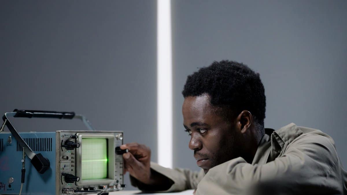Focused man examining oscilloscope signal in a studio setting.