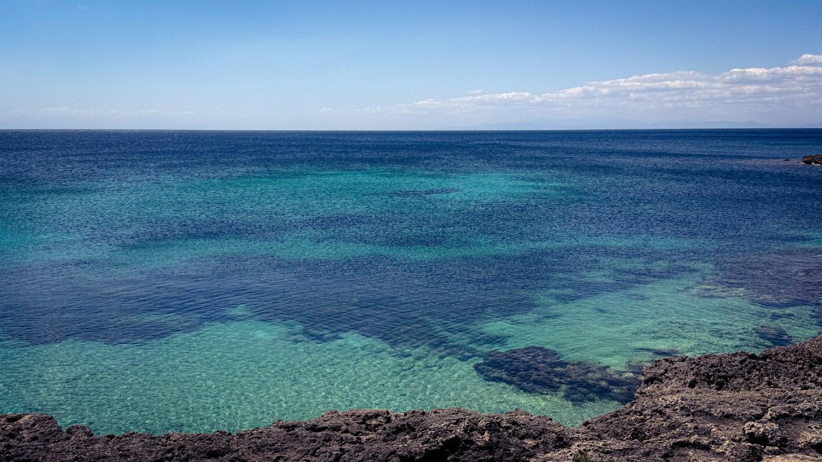 Breathtaking coastal view of clear turquoise ocean water under a bright blue sky.