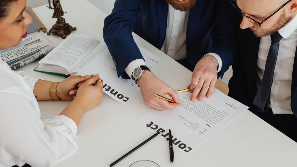 Business professionals engaged in contract review at a modern office desk.