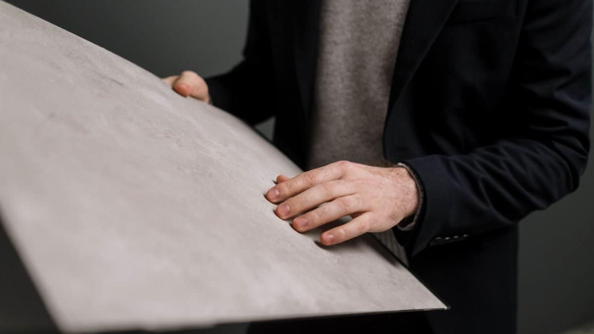 Close-up of a man in business attire examining a large gray panel indoors.