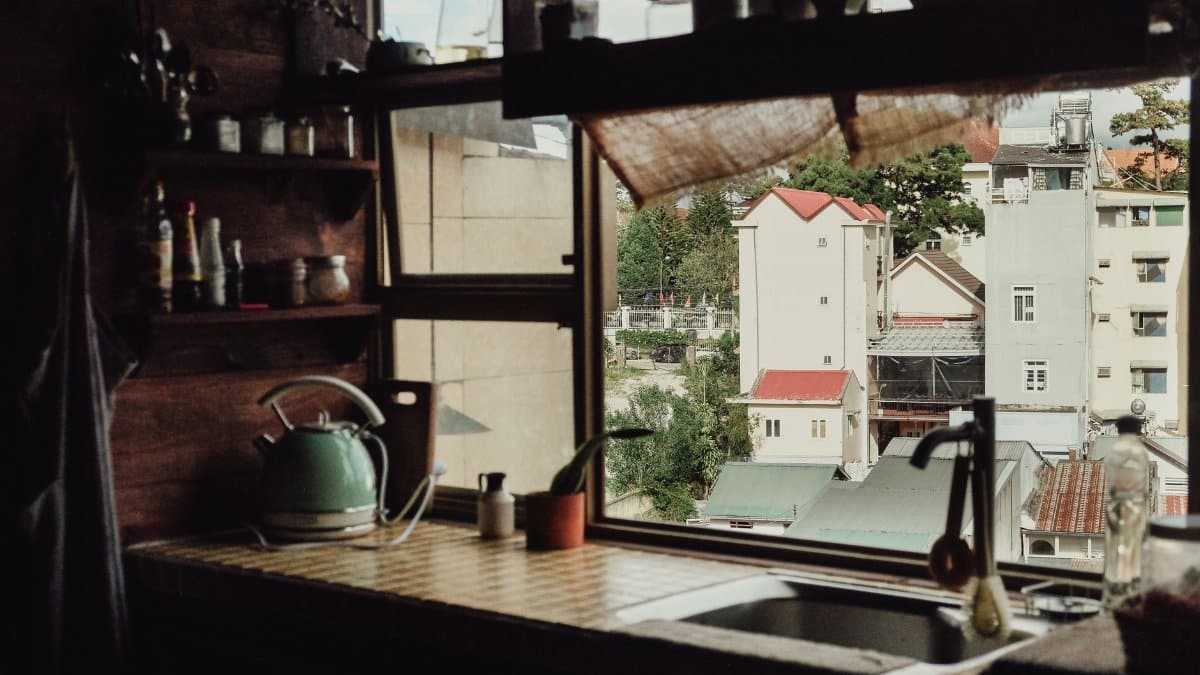 Charming kitchen interior overlooking a quaint urban neighborhood through a window.