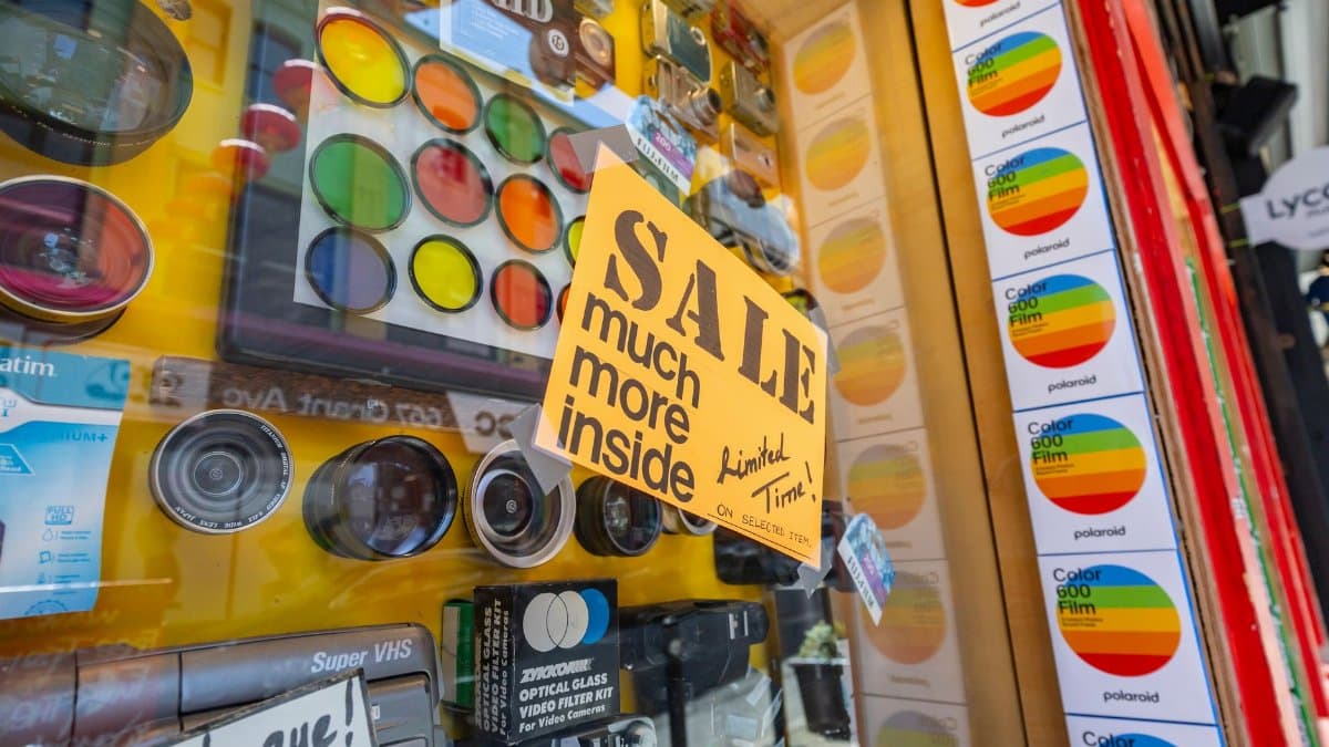 Vibrant display of camera lenses and accessories with a sale sign in a shop window.