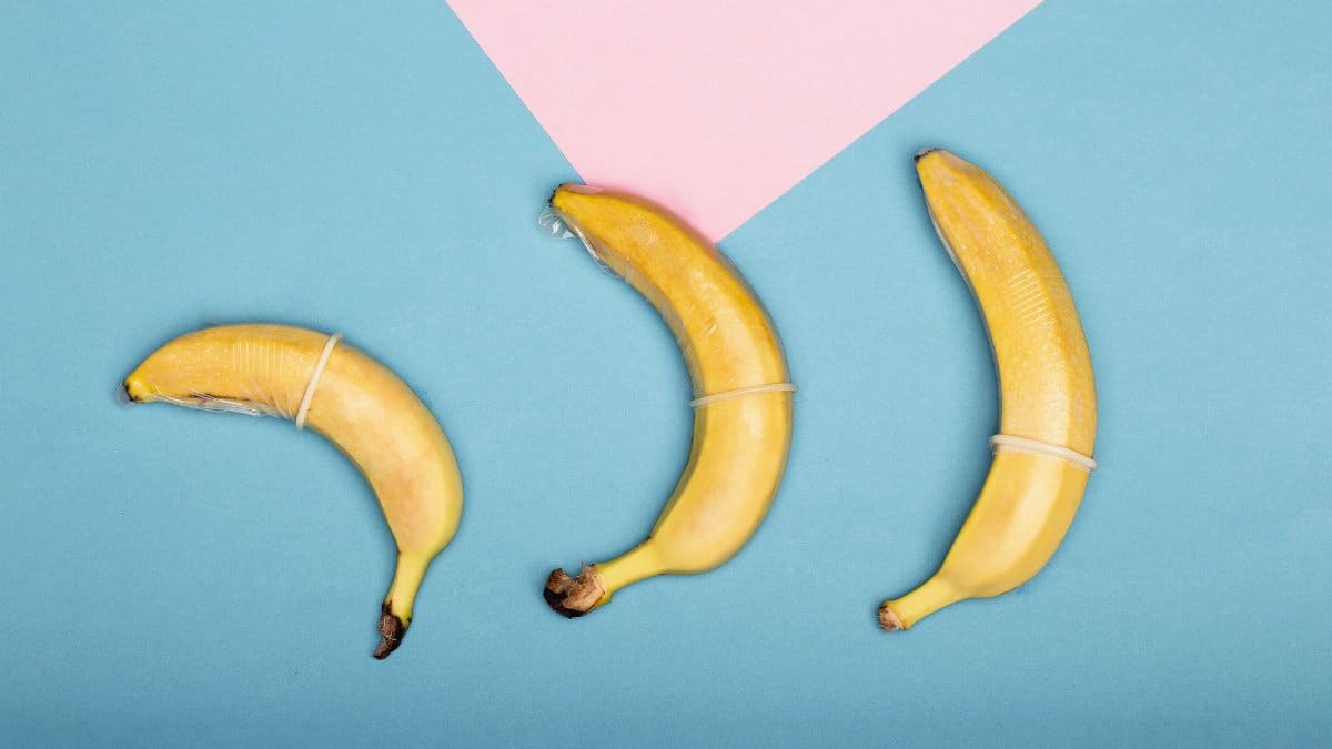 Three bananas wrapped in condoms on a colorful background symbolizing safe sex in a creative way.