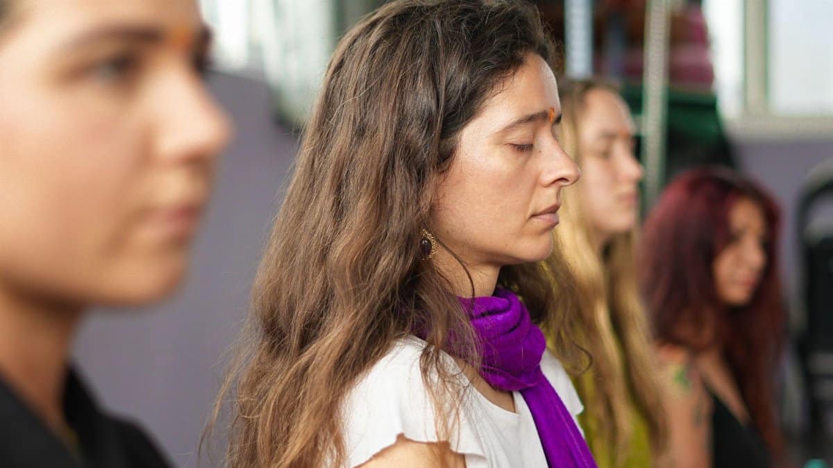 A group of women meditating indoors at an Indian ashram, focusing on mindfulness.