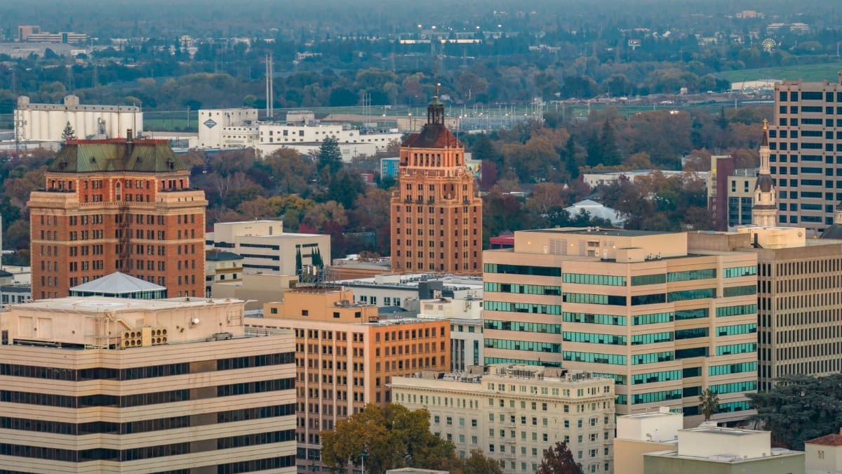 Aerial shot of downtown Sacramento, showcasing iconic buildings and autumn foliage at sunset.