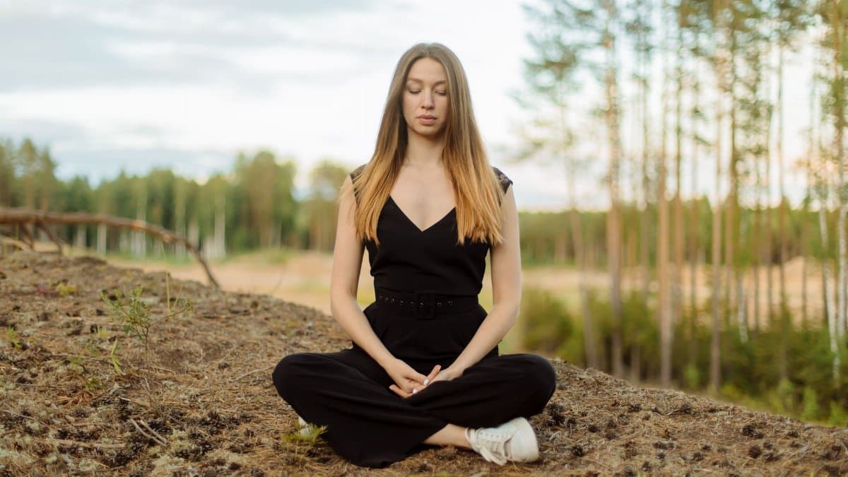 Caucasian woman meditating outdoors, embodying mindfulness and peace in a serene setting.