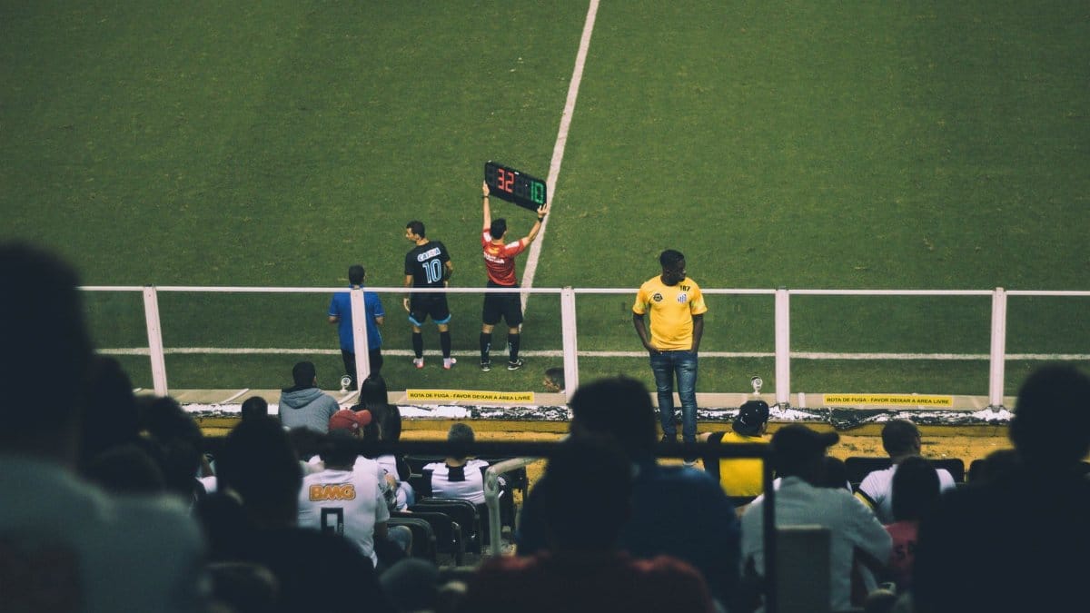 Soccer player substitution during a match at a stadium with an engaged audience.