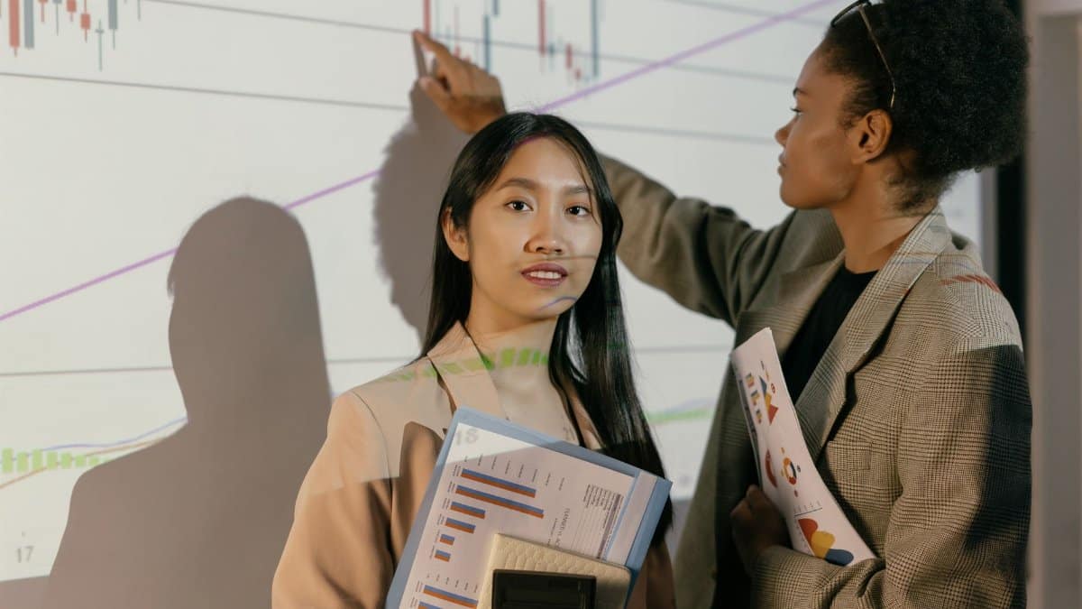Two businesswomen analyze financial projections, showing leadership and teamwork.