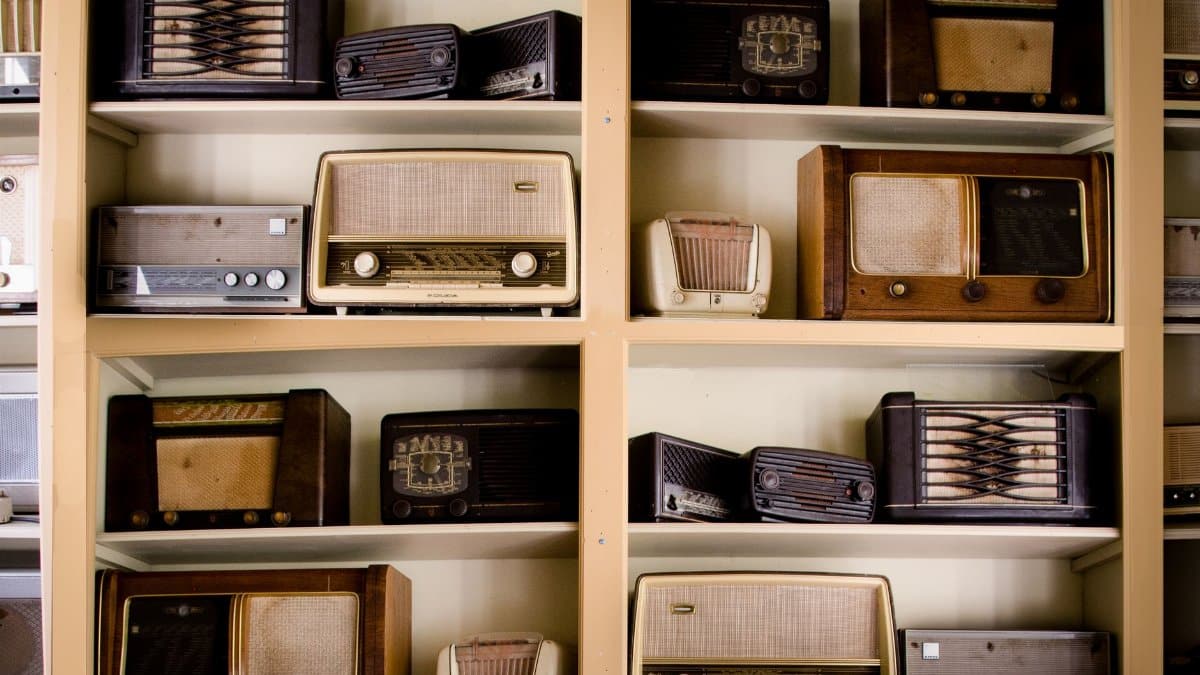A curated collection of vintage radios displayed on shelves in an antique store, showcasing retro designs.