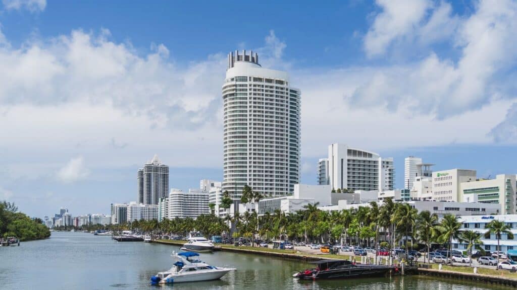 Scenic view of Miami Beach skyline with luxurious waterfront and yachts under a blue sky.