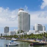 Scenic view of Miami Beach skyline with luxurious waterfront and yachts under a blue sky.