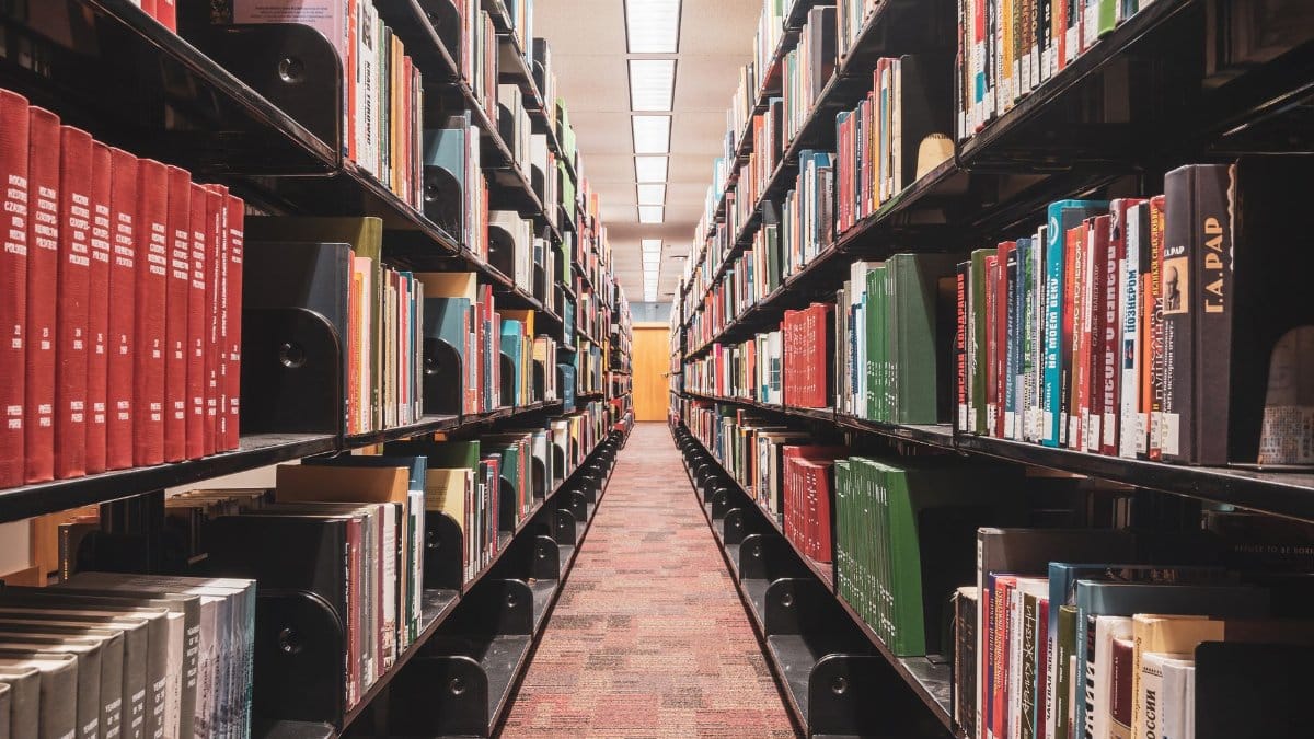 Long corridor of library bookshelves showcasing diverse textbooks and literature.