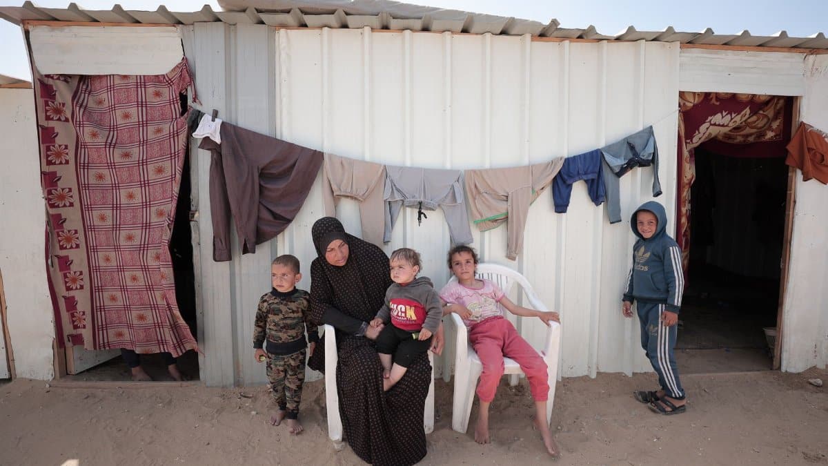 Mother and children outside a makeshift home, showcasing resilience.