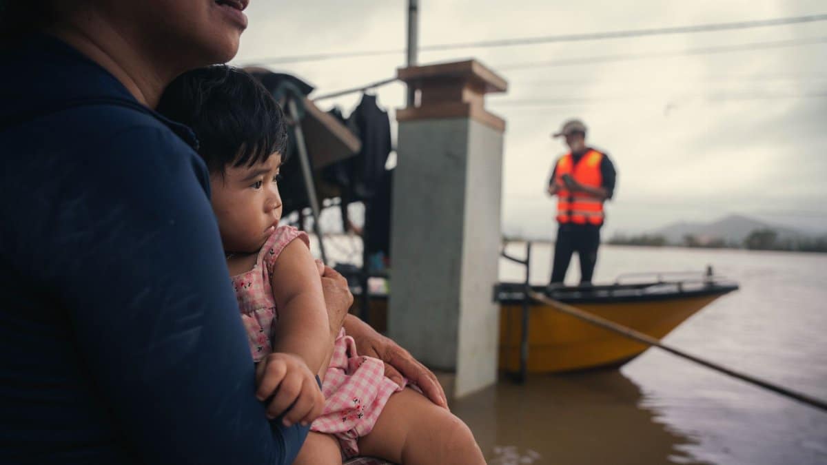 A mother holds her child amid floodwaters in Phú Yên, Vietnam, showcasing resilience and community support.
