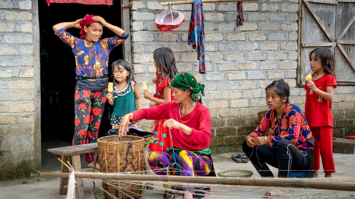 A family engages in daily activities outside a rural house.