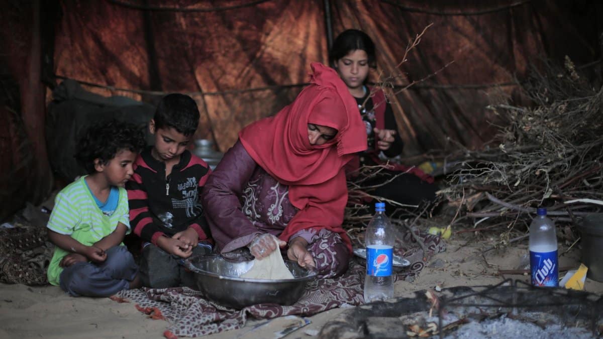A family preparing food together in a traditional tent setup, depicting daily life.
