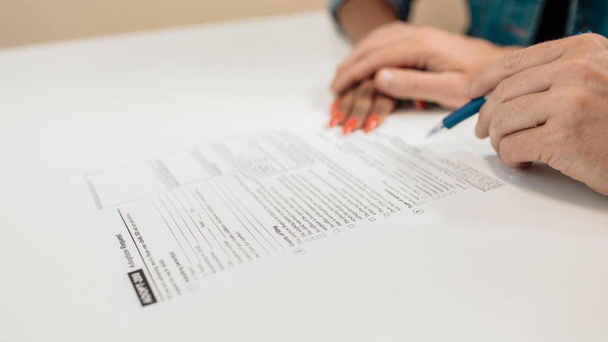 Close-up of hands signing adoption papers in an office environment, symbolizing family and legal process.