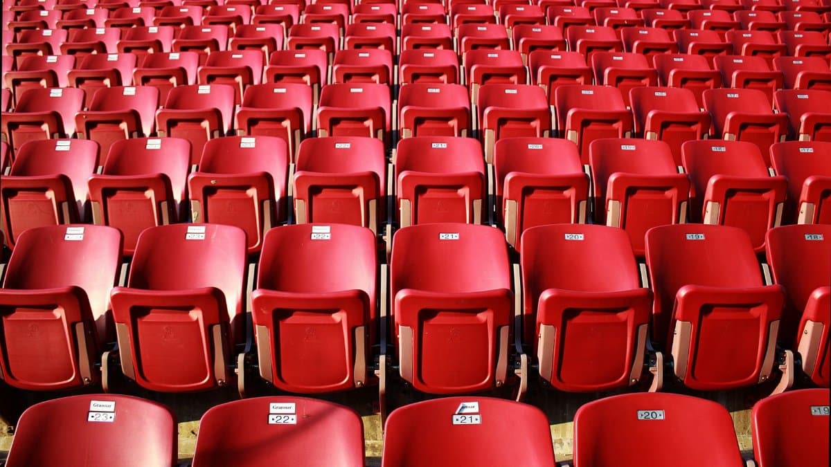 Rows of empty red seats in a stadium, offering a vivid and symmetrical view.