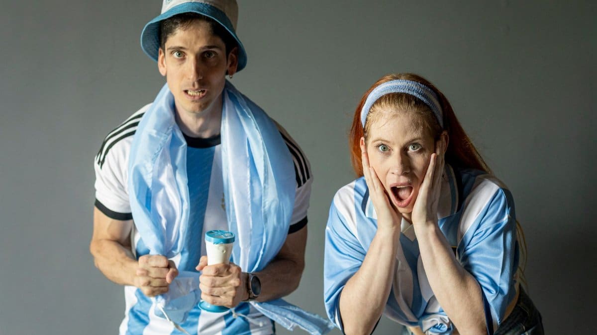 Two passionate Argentine football fans expressing excitement indoors in Buenos Aires.
