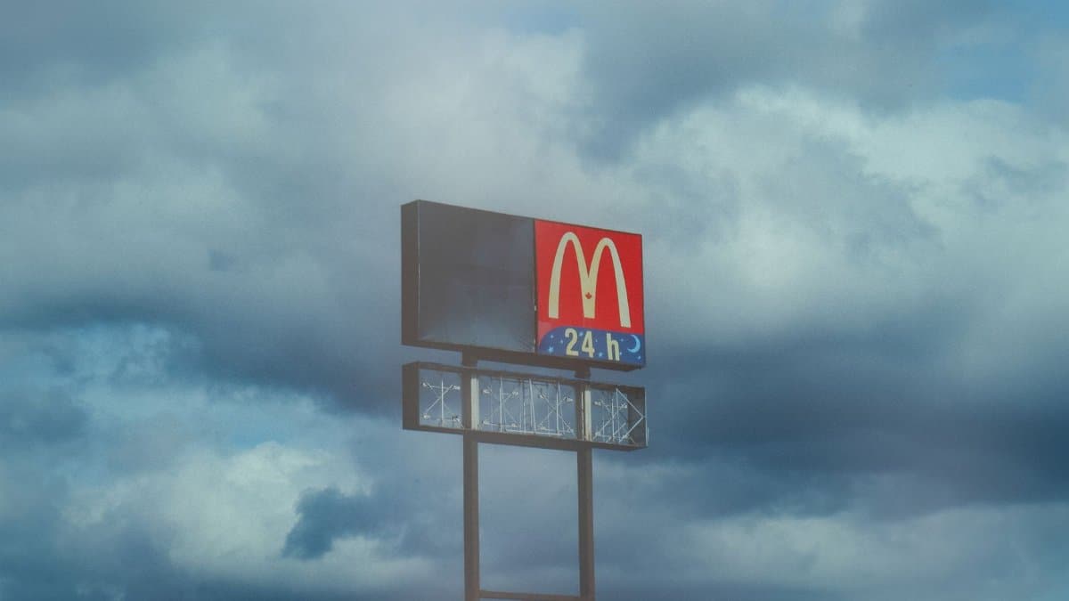 A McDonald's sign prominently stands against a dramatic cloudy sky, symbolizing fast food availability.