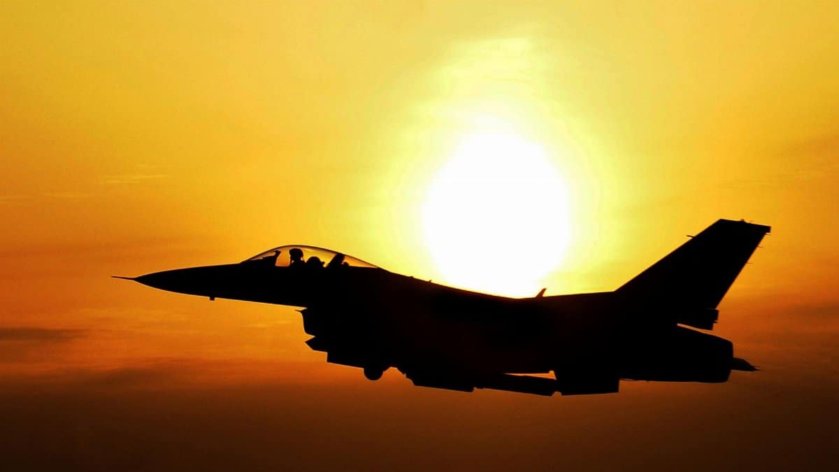 Silhouette of a fighter jet flying during sunrise, highlighting aviation and defense themes.