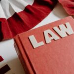 A law book with bold letters placed beside a red, white, and black decorative ribbon.