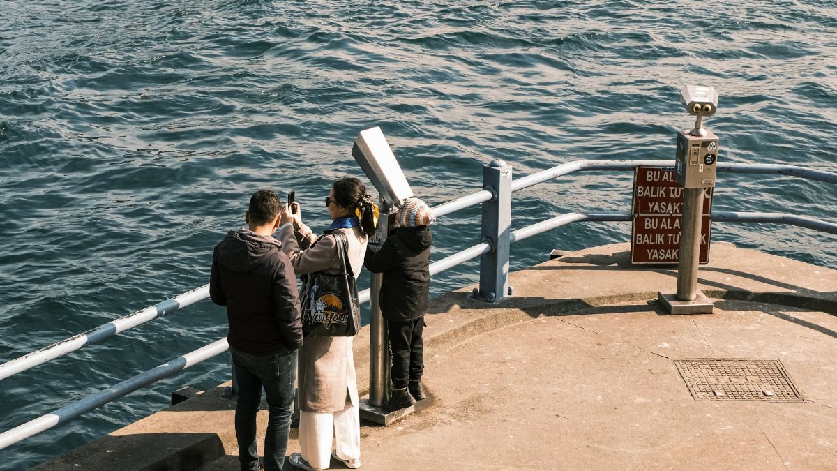 Tourists taking photos by the waterfront in Istanbul, capturing a scenic view.