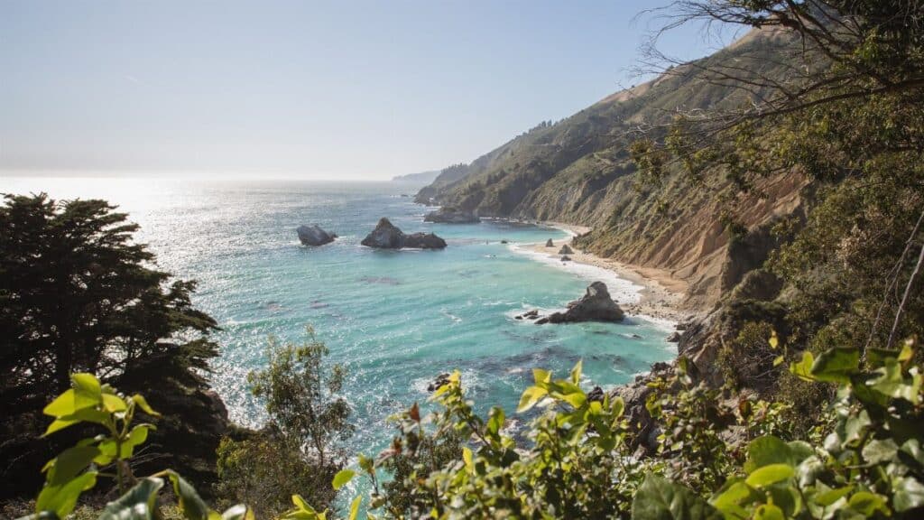 Experience the breathtaking coastal landscape of Big Sur with turquoise waters and lush greenery.